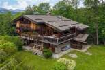 Experience the charm of this stunning wooden chalet nestled amidst lush greenery and majestic mountains.