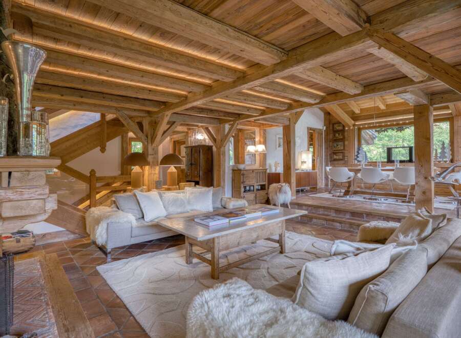 Experience rustic luxury in this stunning living room, featuring exposed wooden beams, a grand stone fireplace, and plush, comfortable seating.