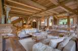 Experience rustic luxury in this stunning living room, featuring exposed wooden beams, a grand stone fireplace, and plush, comfortable seating.