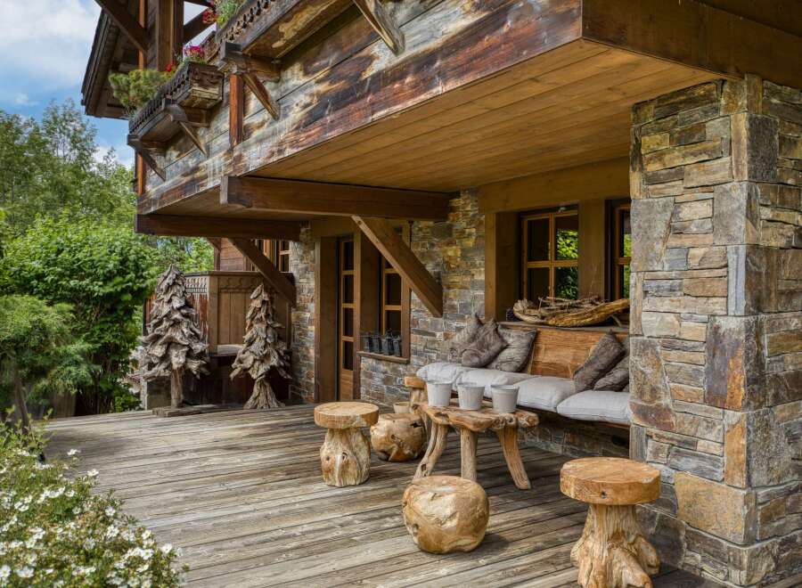 Experience rustic charm on this wooden deck, featuring unique tree-stump stools and a comfortable outdoor seating area.