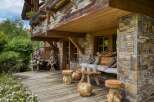 Experience rustic charm on this wooden deck, featuring unique tree-stump stools and a comfortable outdoor seating area.