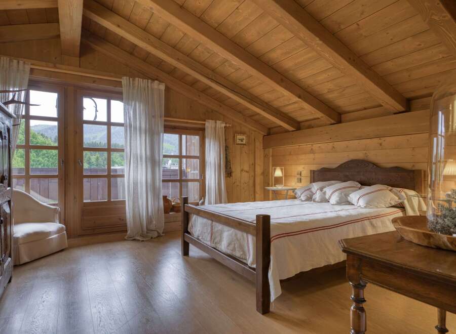Experience rustic charm in this beautifully appointed wooden bedroom, featuring a cozy bed with crisp white linens and red striped accents.