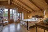 Experience rustic charm in this beautifully appointed wooden bedroom, featuring a cozy bed with crisp white linens and red striped accents.