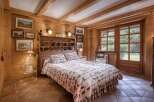 Experience rustic charm in this beautifully appointed bedroom, featuring warm wooden walls and exposed beams.
