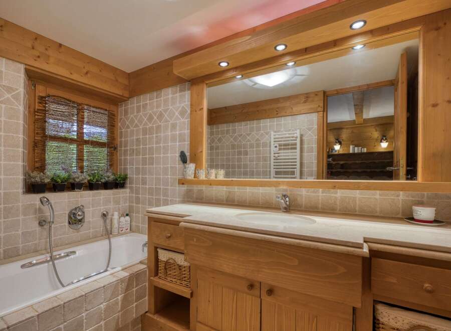 Experience rustic charm in this beautifully appointed bathroom, featuring a deep soaking tub and a spacious wooden vanity with a marble countertop.