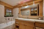Experience rustic charm in this beautifully appointed bathroom, featuring a deep soaking tub and a spacious wooden vanity with a marble countertop.