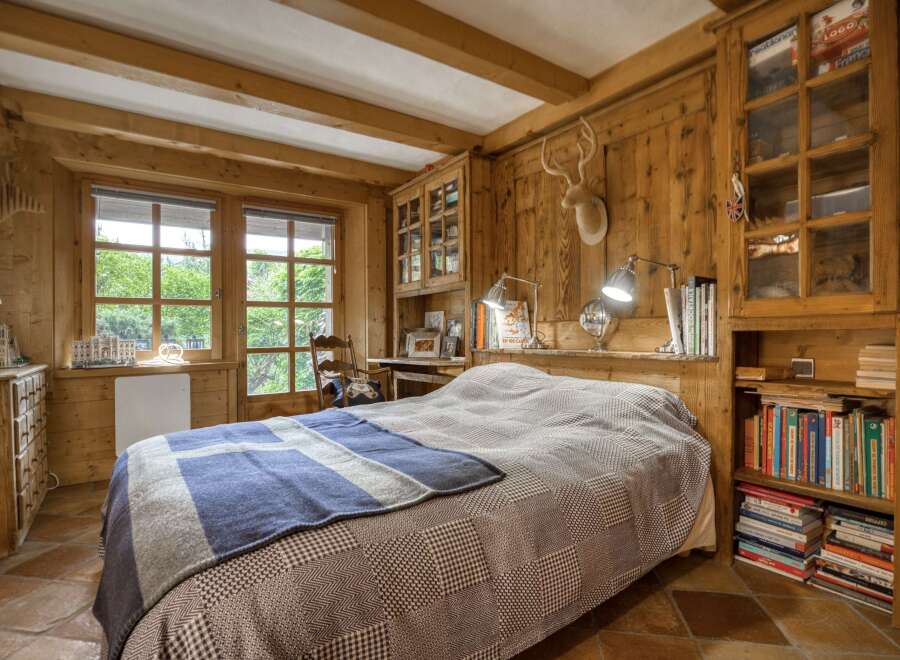 Experience rustic charm in this cozy bedroom, featuring warm wooden walls and exposed beams.