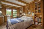 Experience rustic charm in this cozy bedroom, featuring warm wooden walls and exposed beams.