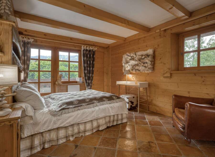Experience rustic charm in this cozy bedroom, featuring warm wooden walls and exposed beams.