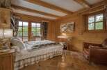 Experience rustic charm in this cozy bedroom, featuring warm wooden walls and exposed beams.