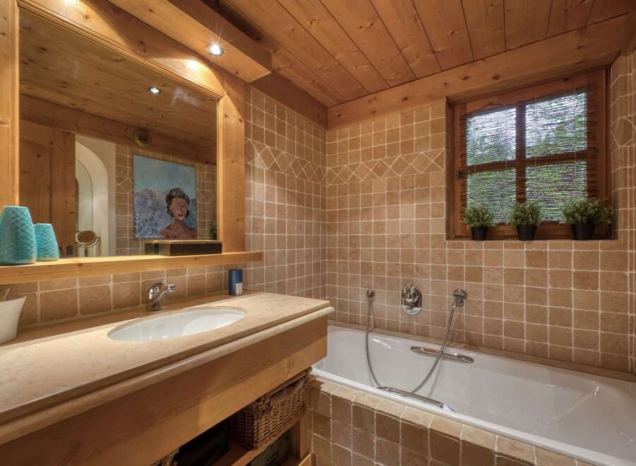 Experience rustic charm in this bathroom featuring warm wooden ceilings and walls complemented by earthy-toned square tiles.