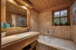 Experience rustic charm in this bathroom featuring warm wooden ceilings and walls complemented by earthy-toned square tiles.