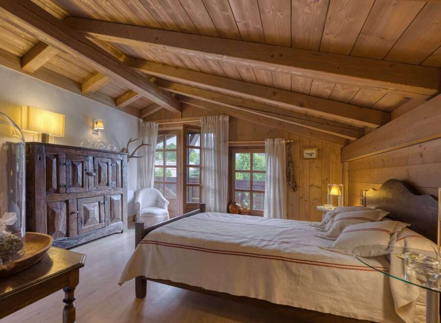Experience rustic charm in this cozy bedroom, featuring a beautifully crafted wooden ceiling with exposed beams and warm, inviting lighting.