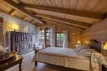 Experience rustic charm in this cozy bedroom, featuring a beautifully crafted wooden ceiling with exposed beams and warm, inviting lighting.