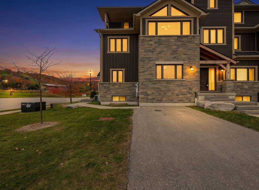 Experience luxury living in this stunning modern townhouse, perfectly situated against a backdrop of rolling hills and a vibrant sunset.