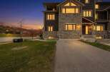 Experience luxury living in this stunning modern townhouse, perfectly situated against a backdrop of rolling hills and a vibrant sunset.