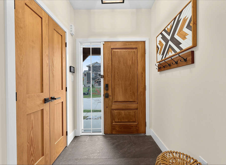 Step into a welcoming entryway featuring warm wood doors and a stylish geometric wall art piece.