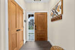 Step into a welcoming entryway featuring warm wood doors and a stylish geometric wall art piece.