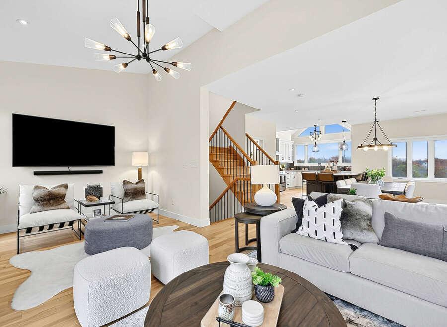 Experience modern living in this spacious open-concept home, featuring a stunning vaulted ceiling with a contemporary chandelier and a large flat-screen TV mounted above a sleek soundbar.