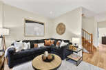 Step into this inviting living room, featuring a plush, dark sectional sofa adorned with a variety of decorative pillows and a cozy throw blanket.