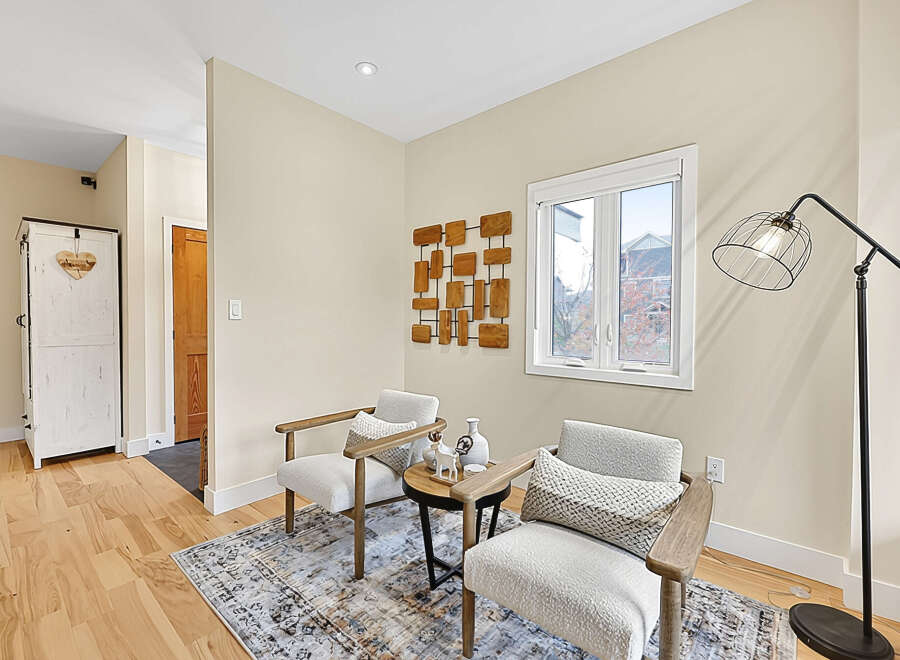 This inviting living space features two plush armchairs perfect for relaxation, complemented by a stylish side table and a decorative wall art.