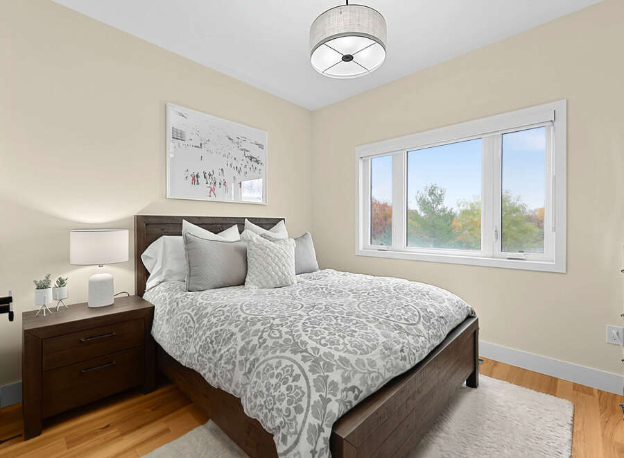 This cozy bedroom features a comfortable queen-size bed with a stylish grey and white patterned comforter, complemented by plush throw pillows.