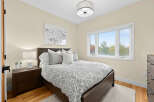 This cozy bedroom features a comfortable queen-size bed with a stylish grey and white patterned comforter, complemented by plush throw pillows.