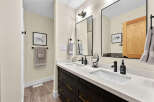 This modern bathroom features a sleek double vanity with dark wood cabinetry and elegant gold hardware.