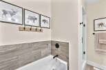 This modern bathroom features a sleek bathtub with marble-patterned tile accents and black fixtures.