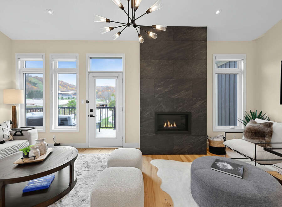 Experience modern living in this beautifully appointed living room, featuring a striking floor-to-ceiling stone fireplace that serves as the room's focal point.