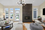 Experience modern living in this beautifully appointed living room, featuring a striking floor-to-ceiling stone fireplace that serves as the room's focal point.