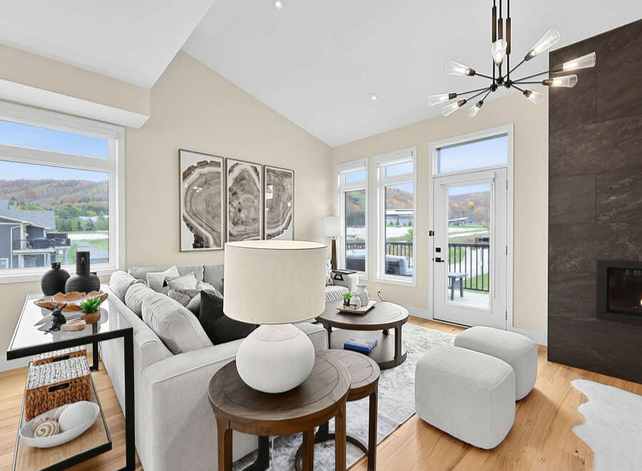 Experience modern living in this stunning living room, featuring a vaulted ceiling and expansive windows that offer breathtaking views of the surrounding landscape.