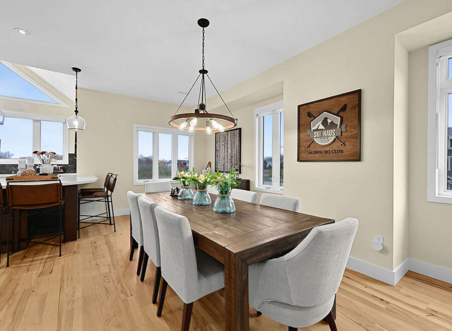 Experience modern living in this stunning dining area, featuring a spacious wooden table perfect for gatherings.
