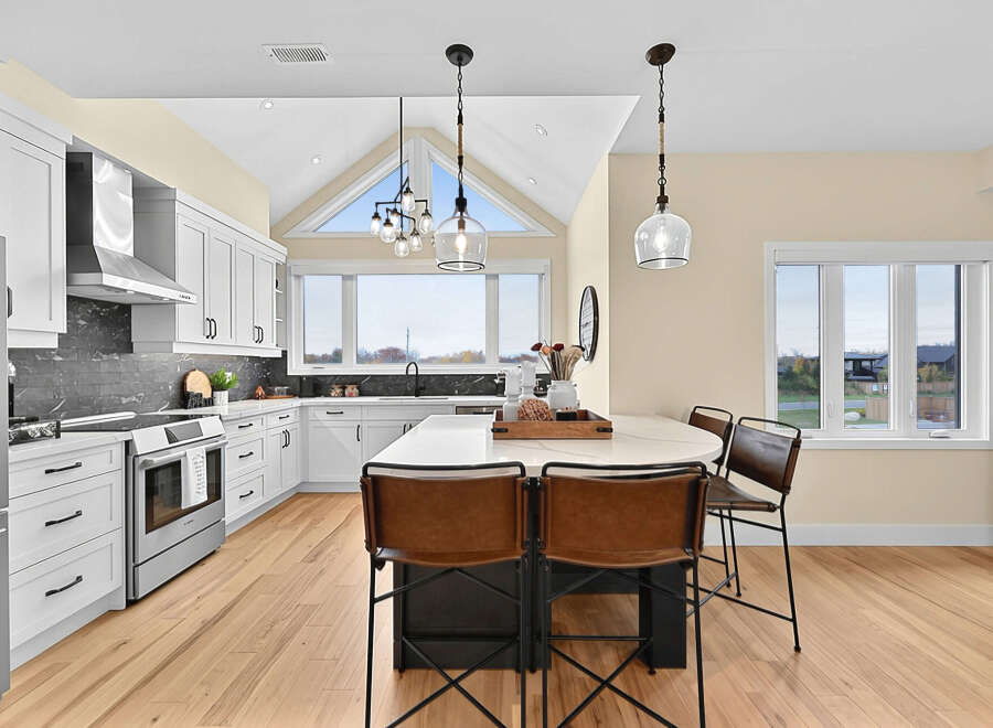 Experience modern living in this stunning kitchen featuring sleek white cabinetry, a dramatic dark backsplash, and a spacious island perfect for entertaining.