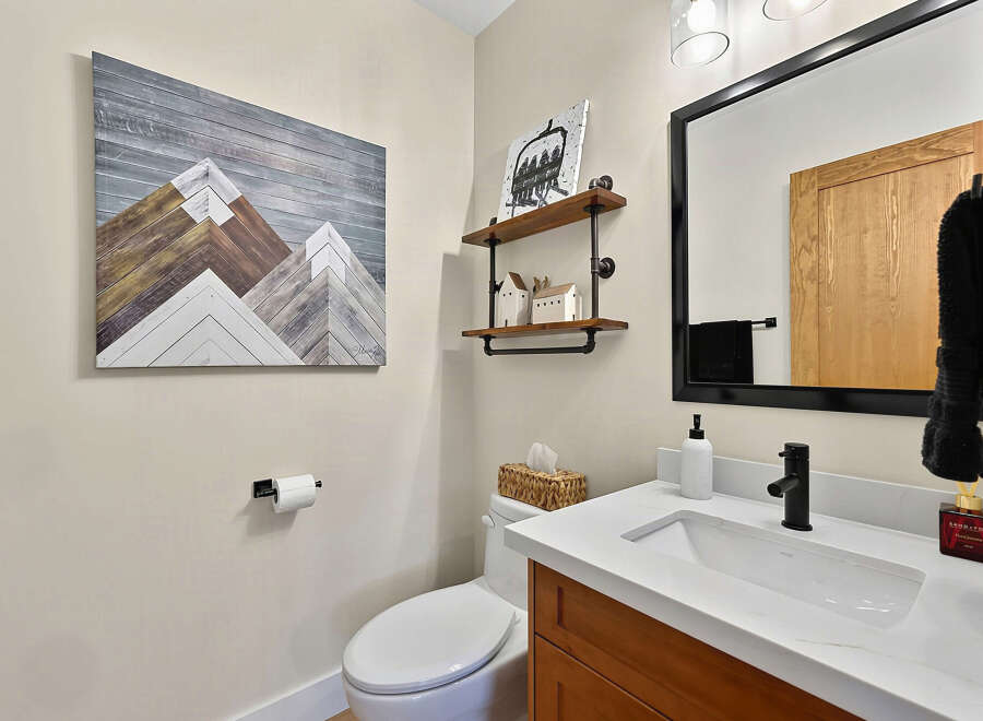 This modern bathroom features a sleek white vanity with a black faucet, complemented by a large black-framed mirror.