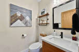 This modern bathroom features a sleek white vanity with a black faucet, complemented by a large black-framed mirror.