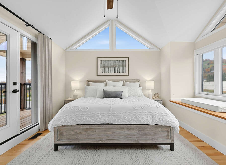 Experience breathtaking views from this stunning bedroom, featuring a vaulted ceiling with triangular windows that flood the space with natural light.