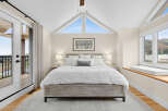 Experience breathtaking views from this stunning bedroom, featuring a vaulted ceiling with triangular windows that flood the space with natural light.