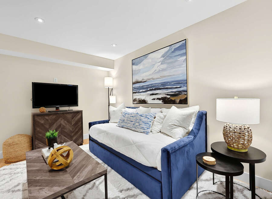 This living area features a plush blue velvet daybed adorned with white and blue patterned pillows, perfect for relaxation.