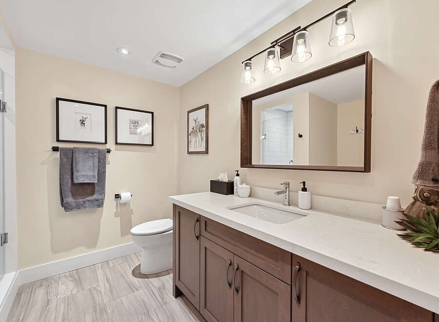 This beautifully appointed bathroom features a modern vanity with a quartz countertop, complemented by a sleek chrome faucet.