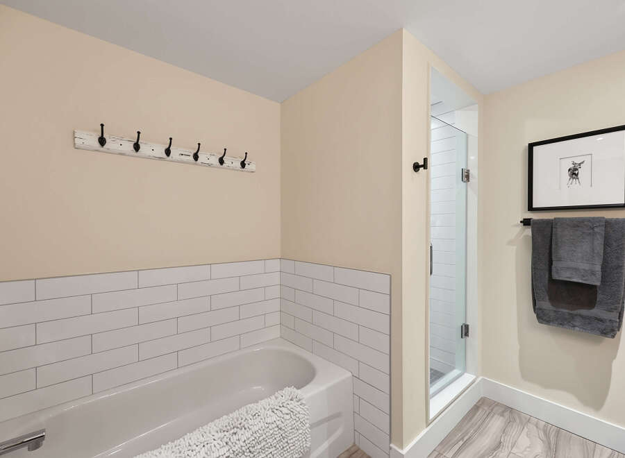 This charming bathroom features a pristine white bathtub complemented by subway tile wainscoting, offering a clean and classic aesthetic.