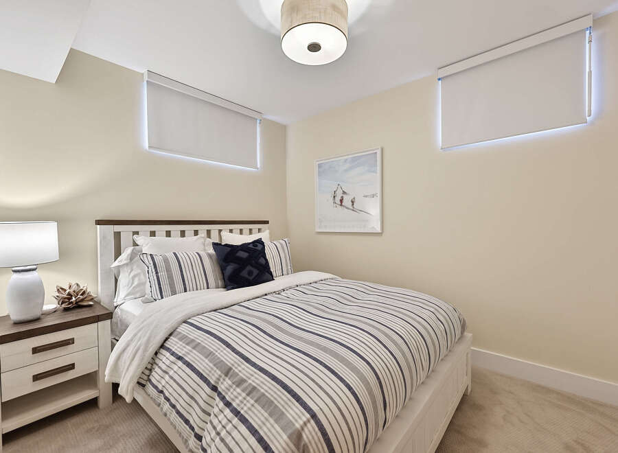 This cozy bedroom features a comfortable queen-size bed with a striped duvet and plush pillows, perfect for a restful night's sleep.