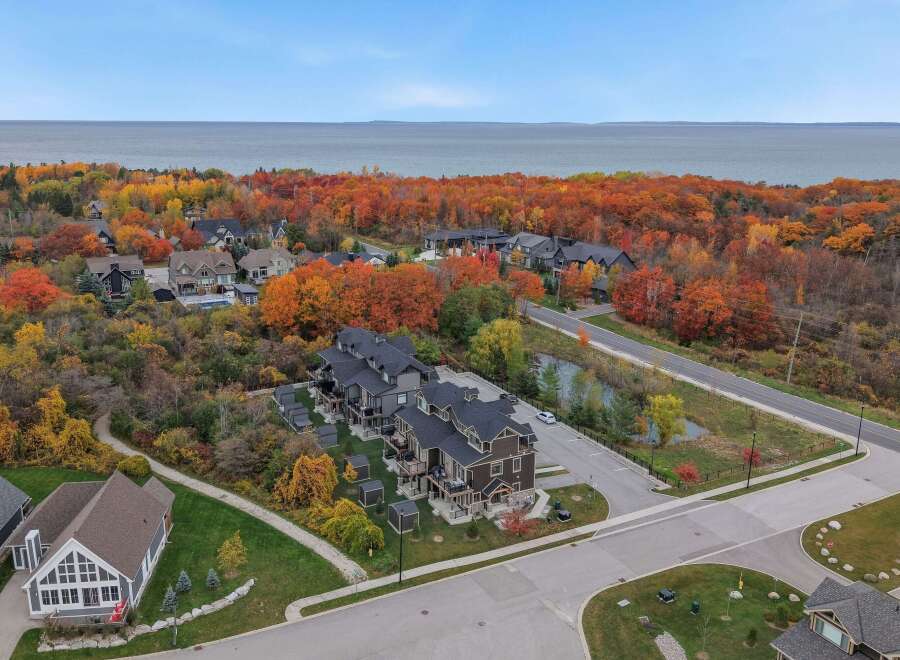 Experience the beauty of autumn from this stunning aerial view, showcasing modern townhomes nestled amidst vibrant fall foliage.