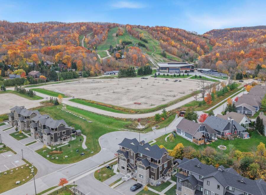 Experience the beauty of autumn from this stunning aerial view, showcasing a vibrant ski resort nestled amidst colorful fall foliage.