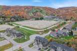 Experience the beauty of autumn from this stunning aerial view, showcasing a vibrant ski resort nestled amidst colorful fall foliage.