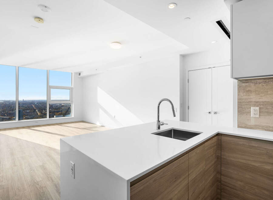 Experience modern living in this stunning apartment featuring a sleek kitchen with a waterfall island and contemporary wood cabinetry.