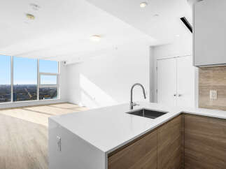 Experience modern living in this stunning apartment featuring a sleek kitchen with a waterfall island and contemporary wood cabinetry.