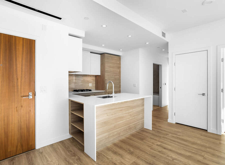Step into this modern kitchen featuring a sleek island with waterfall countertops and integrated shelving.