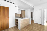 Step into this modern kitchen featuring a sleek island with waterfall countertops and integrated shelving.