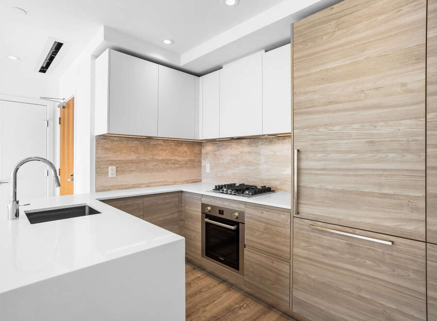 This modern kitchen features sleek white cabinetry contrasted with warm, natural wood accents on the refrigerator and lower cabinets.